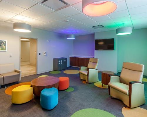 Interior photo of lounge area with colorful lighting, carpeting and seating. 沙发排在墙上.